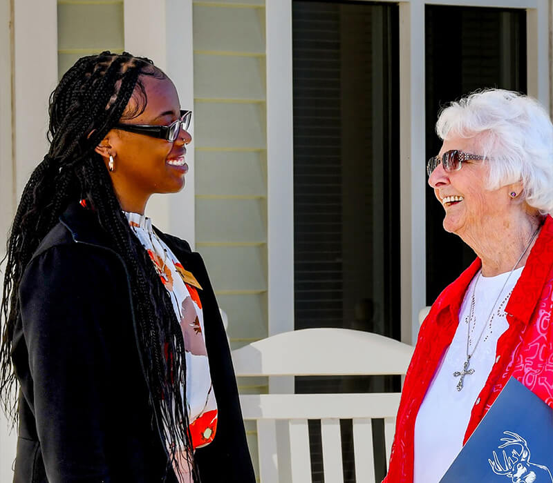 Two women chatting in front of a home